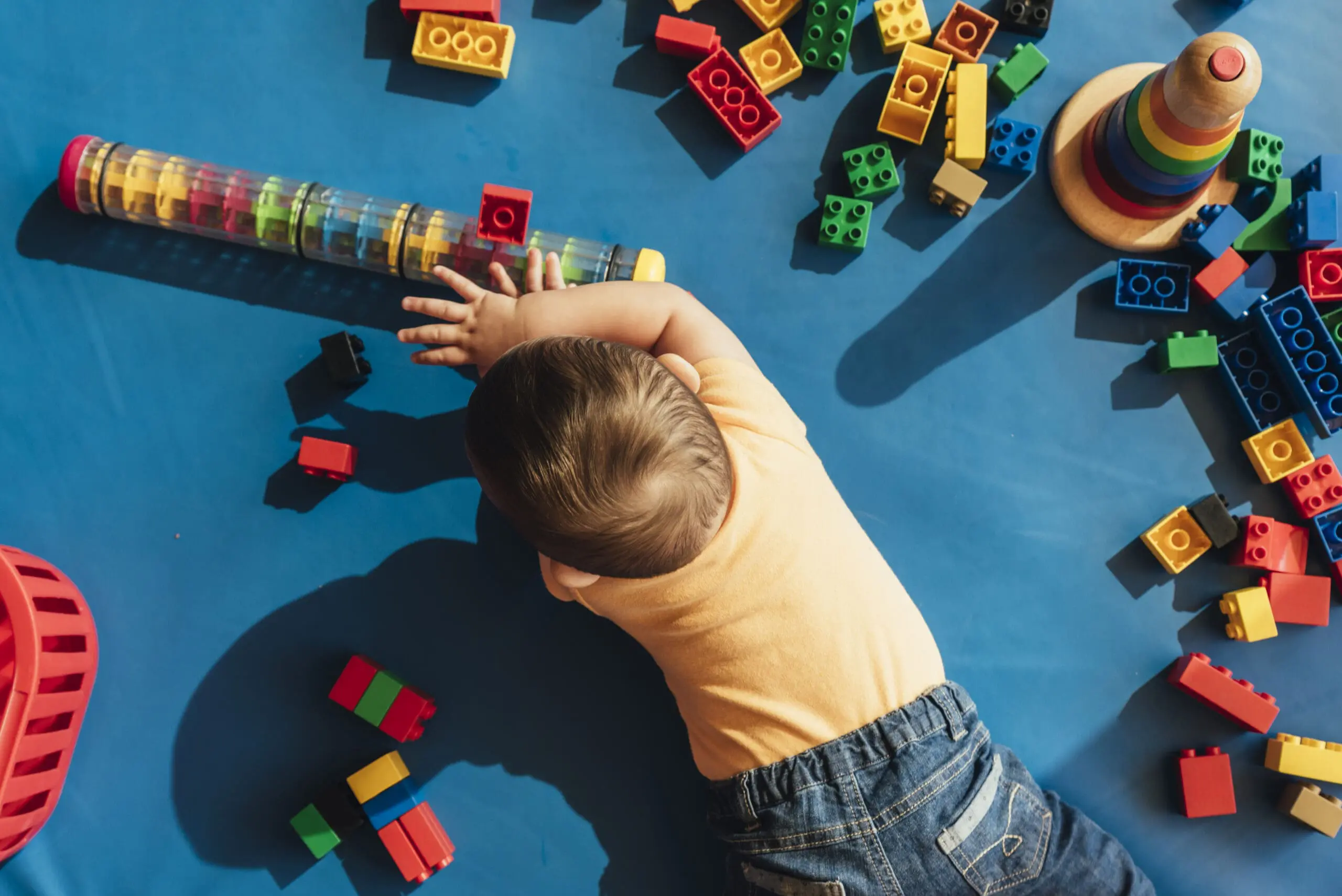 Happy baby playing with toy blocks in the kindergarten.